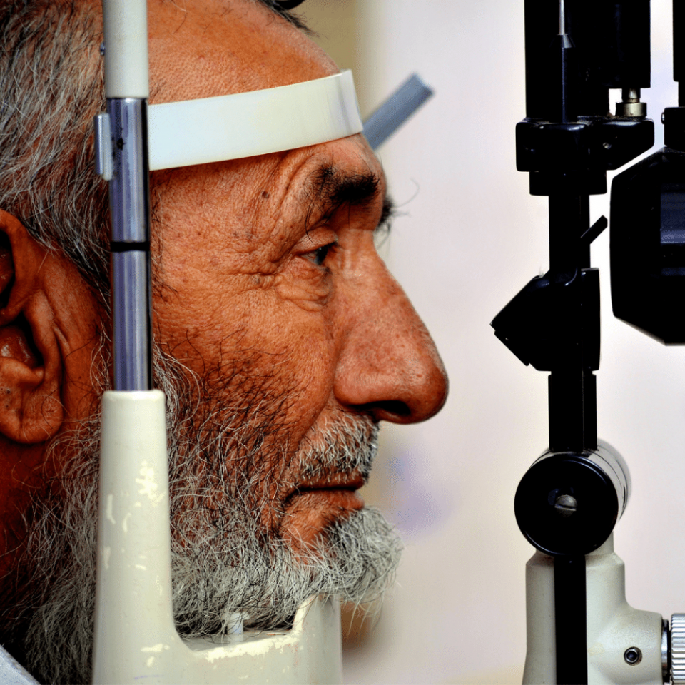 An older man looks through a retinoscope