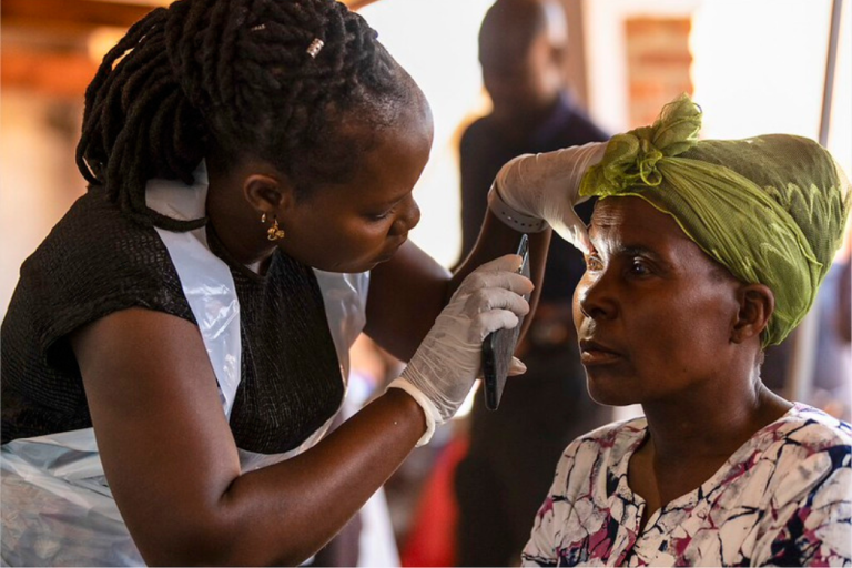 In Malawi, a health worker assesses a woman's eye using the torch on a smartphone